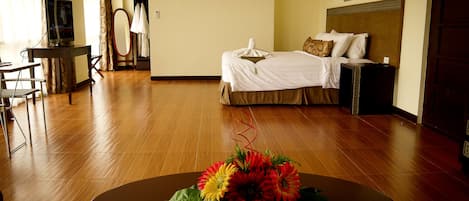 Una habitación de hotel con una cama, un escritorio, una silla y una mesa con flores.