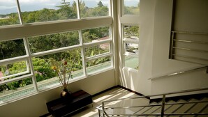 A staircase with a metal railing and a view of greenery outside through large windows. - Fersal Hotel Puerto Princesa (Puerto Princesa)