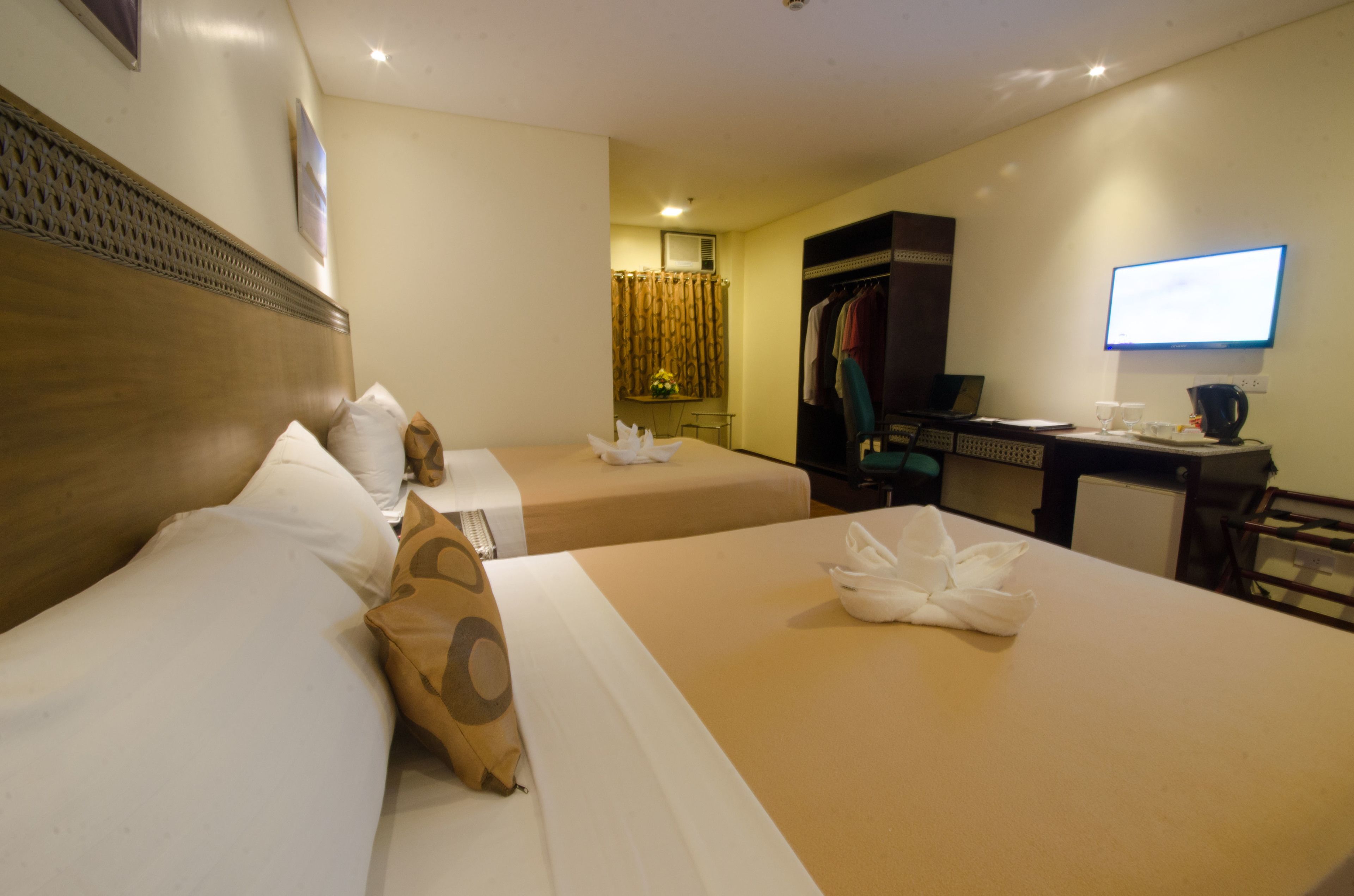 Una habitación de hotel con dos camas, un escritorio, un televisor y un armario.