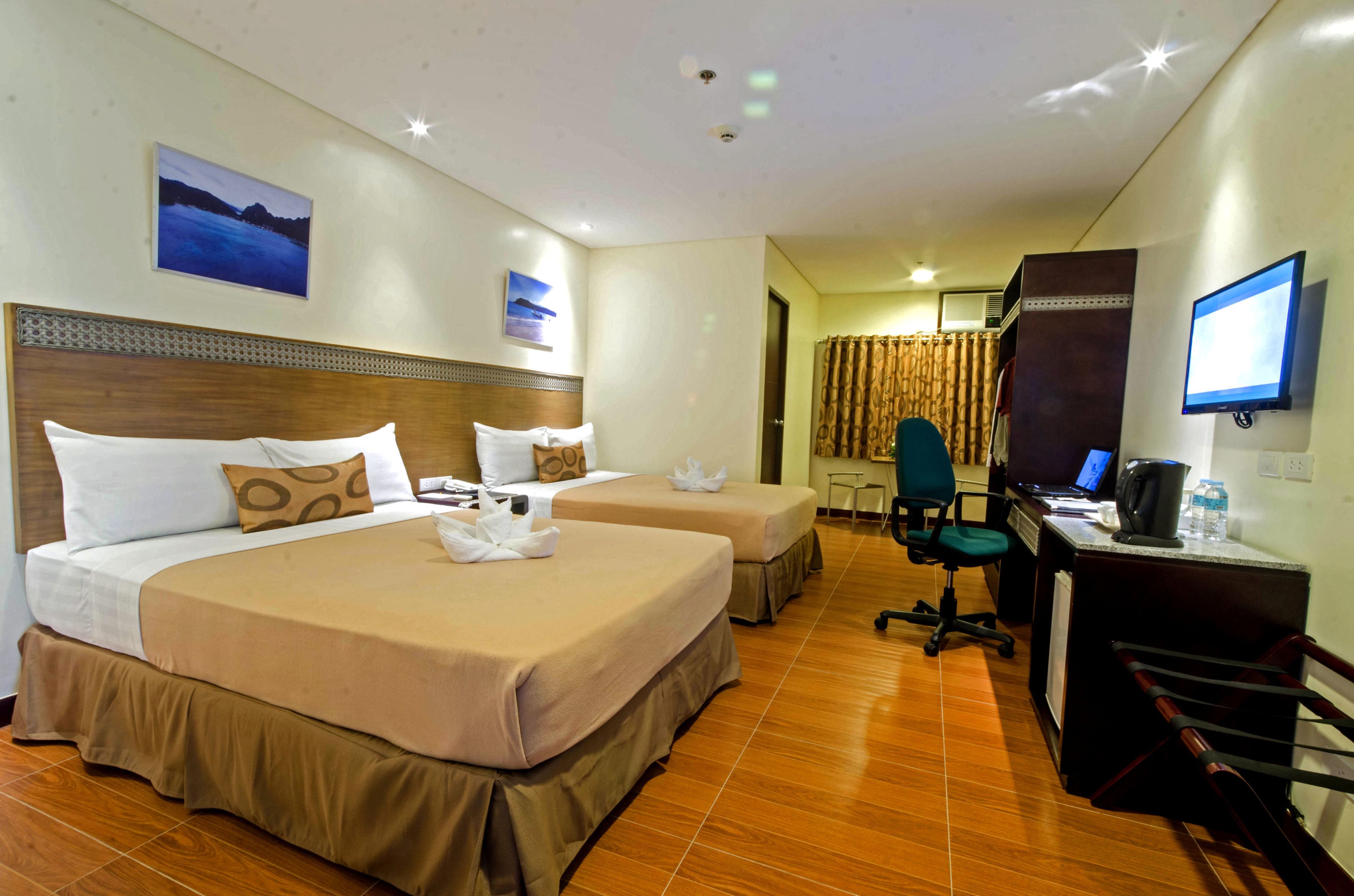 Une chambre d’hôtel avec deux lits, un bureau avec un ordinateur, une chaise et un téléviseur.