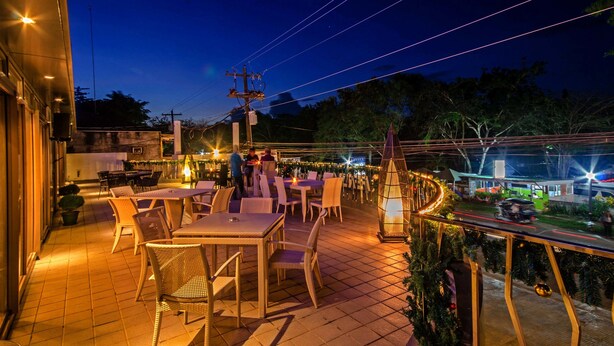 An outdoor patio area with tables and chairs, a street view, and a Christmas tree. - Fersal Hotel Puerto Princesa (Puerto Princesa)