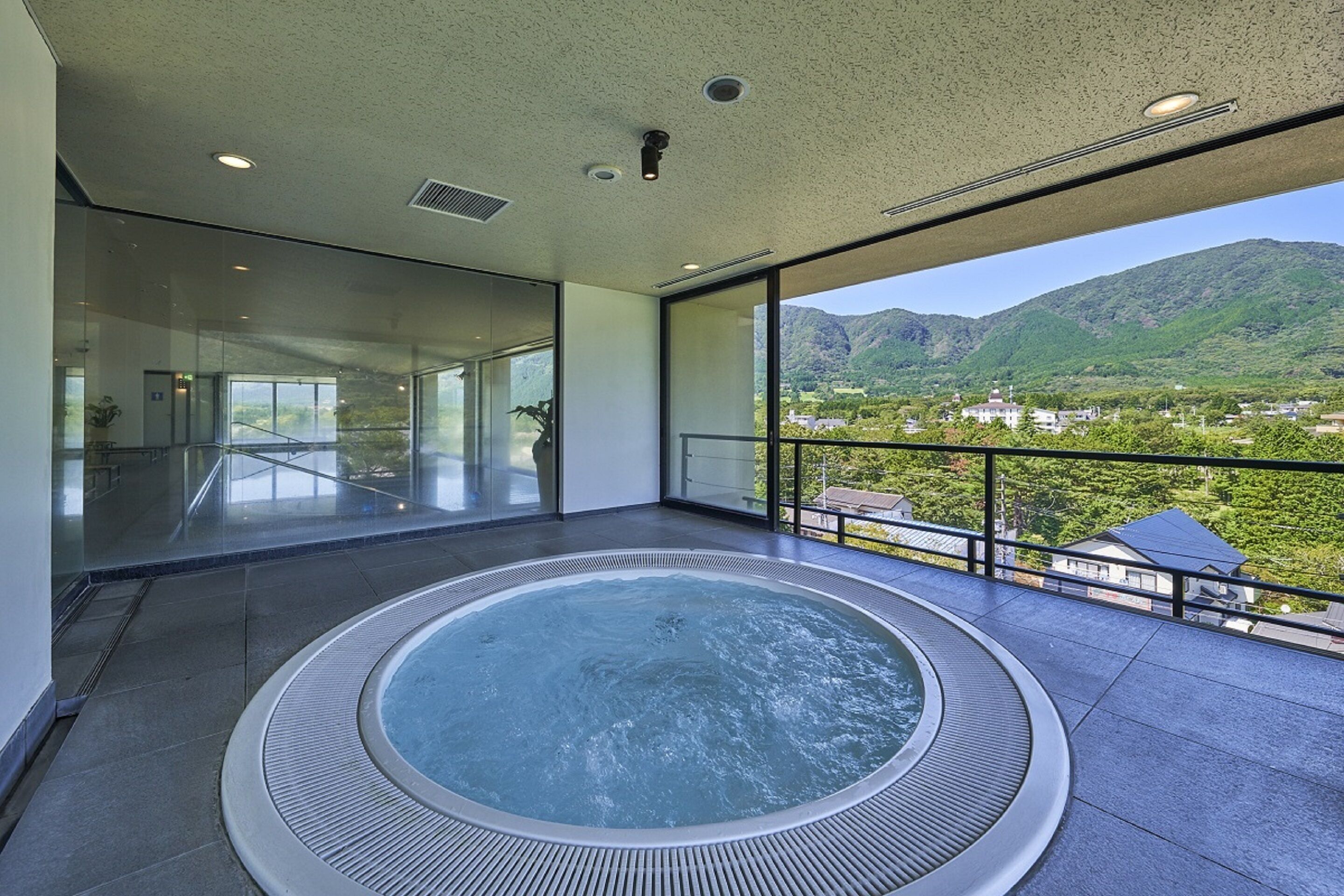 A modern indoor hot tub with a panoramic view of a mountainous landscape.
