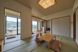 Un interior moderno con suelo de tatami, una mesa de comedor de madera y un televisor en un espacio habitable compacto.