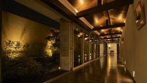Un largo pasillo bien iluminado con vigas de madera, puertas de cristal y suelo de madera.