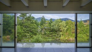 Una habitación con puertas de vidrio amplias que dan a vistas de un jardín exuberante y montañas.