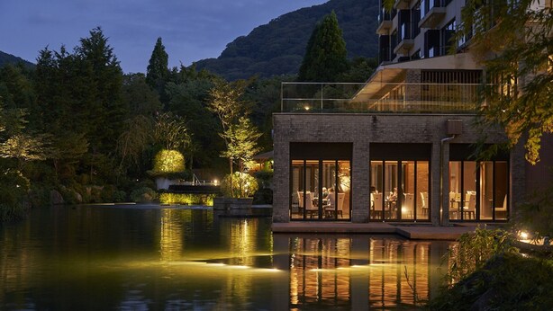 Un edificio moderno con amplios ventanales, una piscina y zonas verdes circundantes.