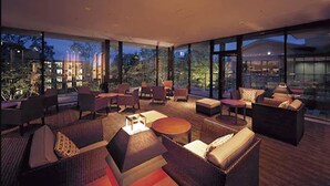 A modern lounge area with comfortable seating, a coffee table, and large windows offering a view of the cityscape. - Hotel Harvest Nasu (Nasu)