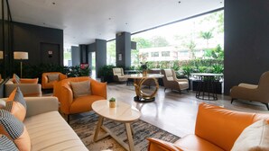 Un vestíbulo amplio con mobiliario moderno, ventanas grandes y plantas de interior.