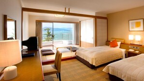 Habitación de hotel con cama, escritorio, silla, televisor y vista al exterior.