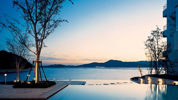 Una piscina infinita con vistas claras al mar y montañas distantes.