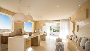 A modern interior with a reception desk, seating area, and large windows. - Sunshine Hotel (Malia)