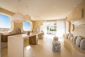 A modern interior with a reception desk, seating area, and large windows. - Sunshine Hotel (Malia)