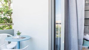 A balcony with a round table, two chairs, and a potted plant. - Sunshine Hotel (Malia)