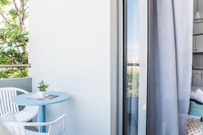 A balcony with a round table, two chairs, and a potted plant. - Sunshine Hotel (Malia)