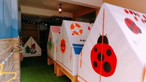 A children's play area with small, colorful tents and a green carpet. - Pon Pon Woo (Kaohsiung)