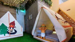 Two small, tent-like structures with a child in one and a fairy in the other, set on artificial grass. - Pon Pon Woo (Kaohsiung)