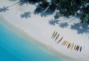 Une plage où une rangée de canoës est alignée sur le sable.
