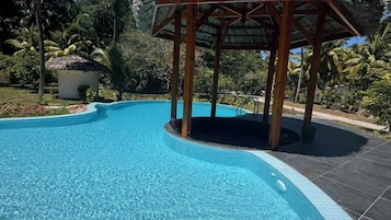 Una piscina al aire libre, sombrillas, sillones reclinables de piscina