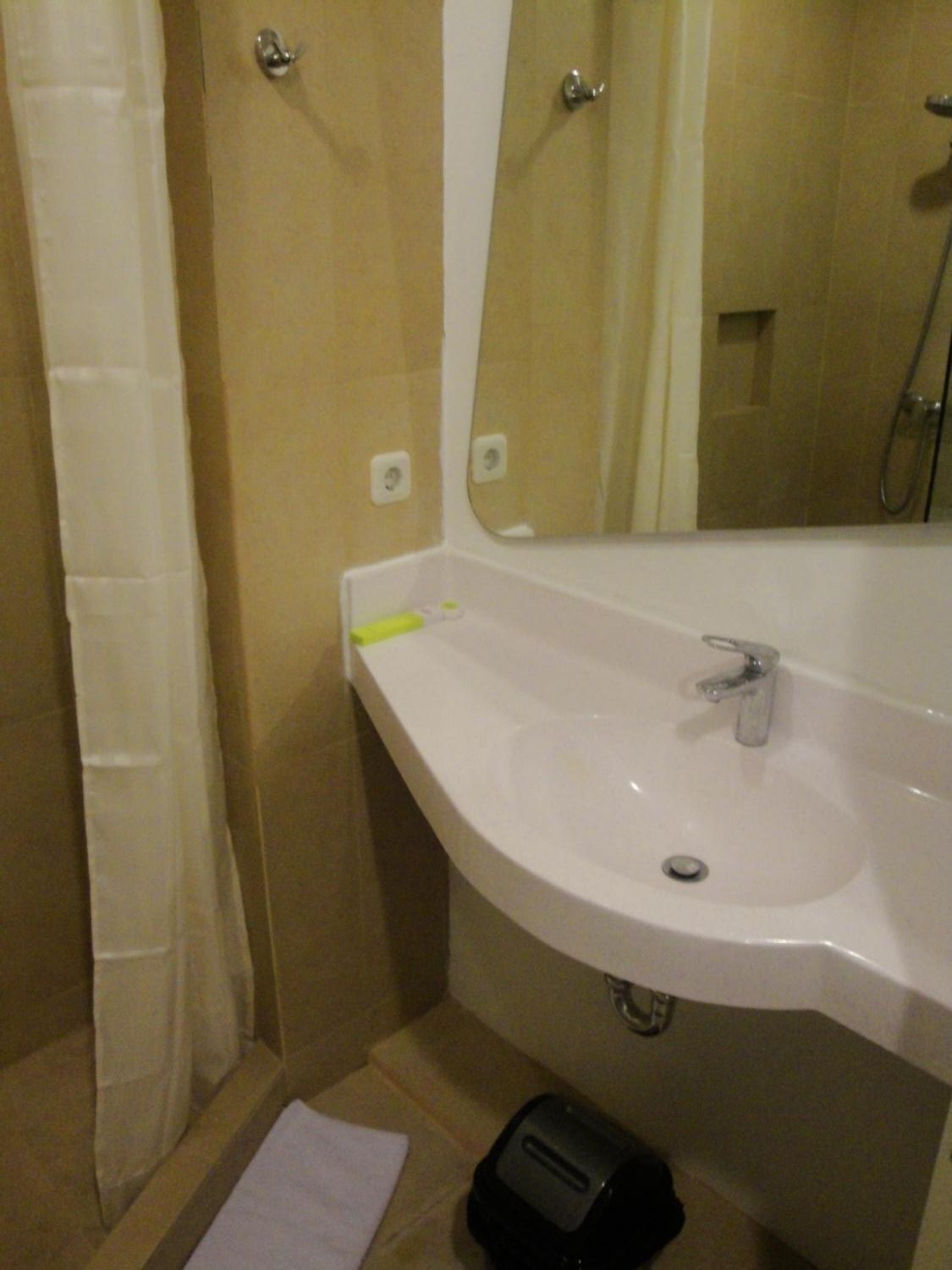 Une salle de bain équipée d’un lavabo, d’un miroir, d’une douche et d’un porte-serviettes.