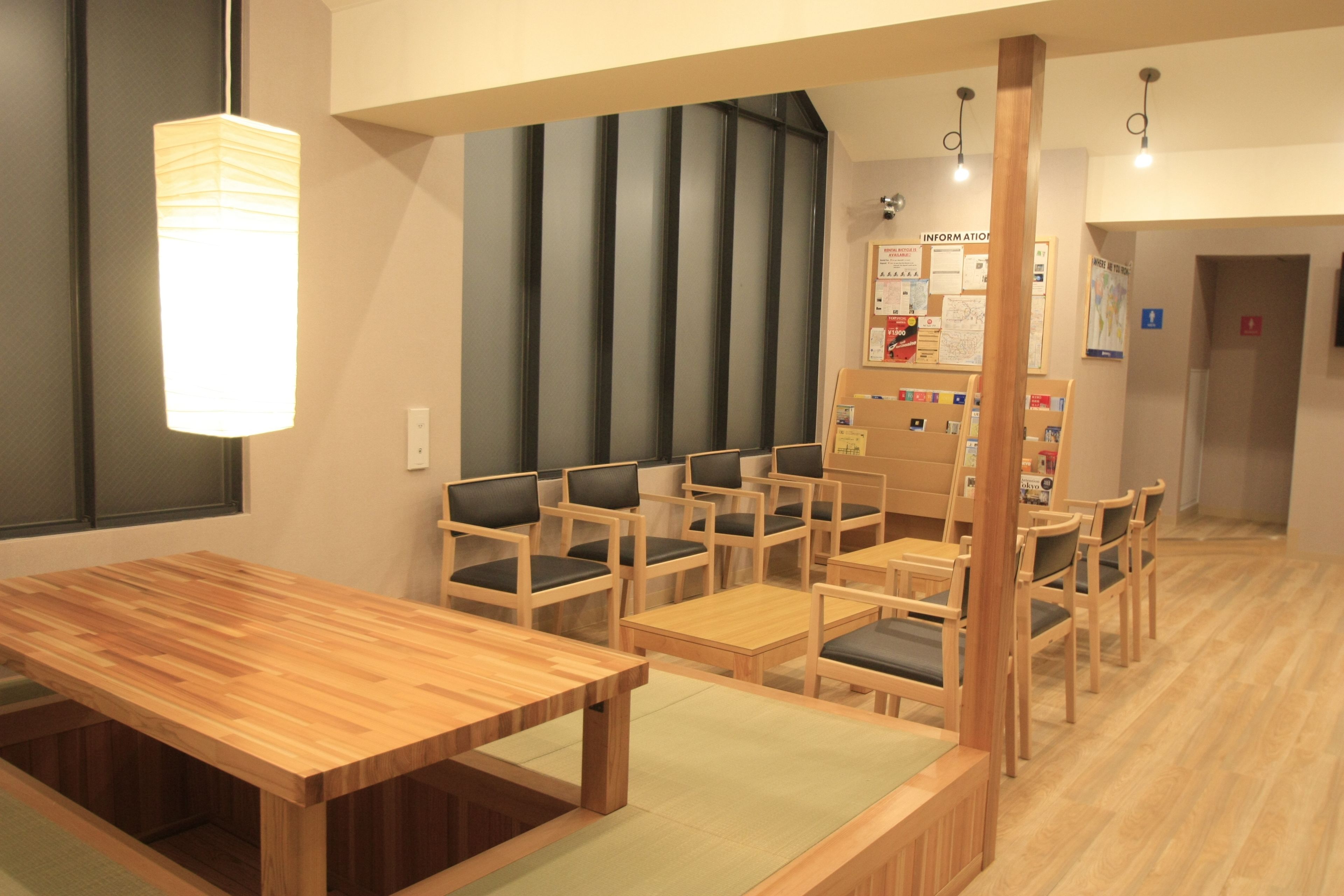 A wooden dining area with tables and chairs, a large window, and a wall with information posters.