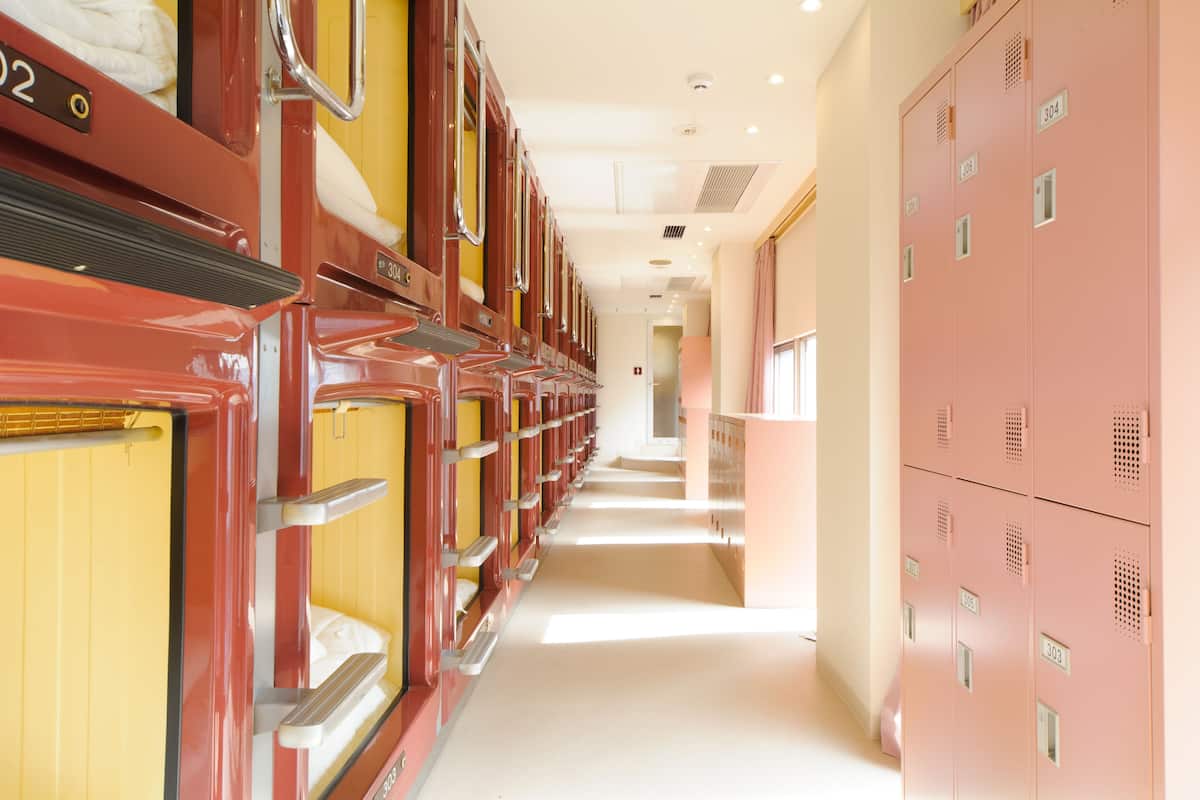 A hotel corridor with rows of lockers and a row of beds.