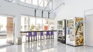 A spacious lobby with high ceilings, large windows, and a vending machine. - Single Inn Taipei - Hostel (New Taipei City)