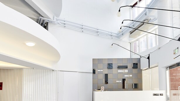 A modern hotel lobby with a curved ceiling, large windows, and a reception desk labeled "SINGLE INN". - Single Inn Taipei - Hostel (New Taipei City)