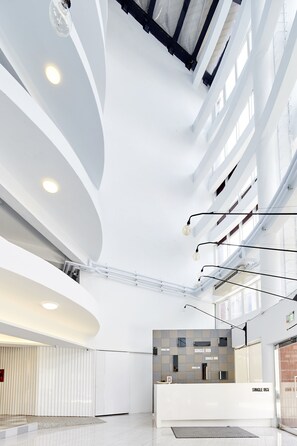 A modern hotel lobby with a curved ceiling, large windows, and a reception desk labeled "SINGLE INN". - Single Inn Taipei - Hostel (New Taipei City)