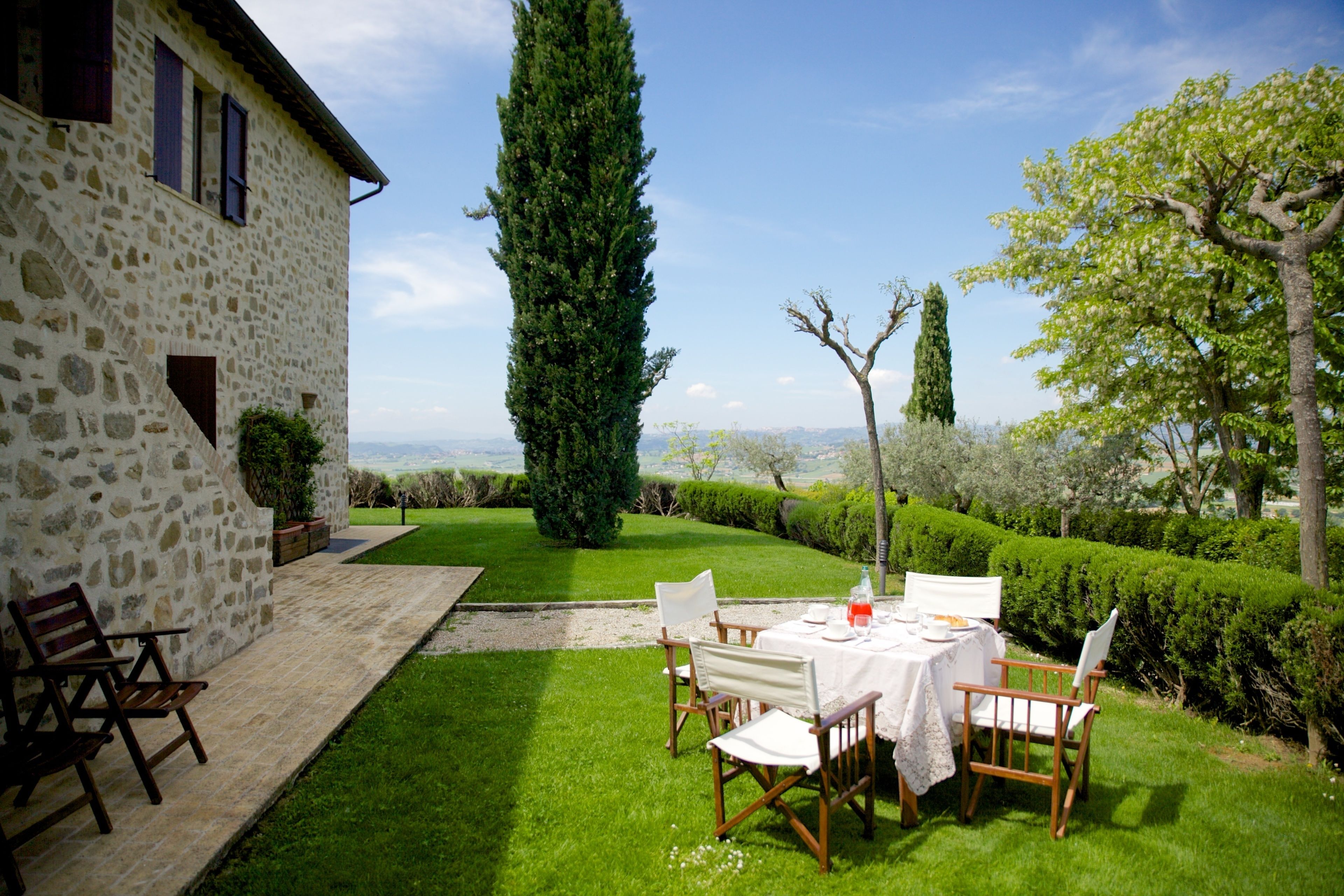 A stone building with a patio, a table set for dining, and a view of the landscape.