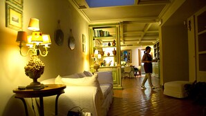 Una camera d'albergo con un letto, un tavolo con una lampada, una libreria e un angolo cottura.