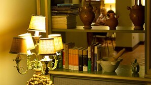 Una stanza con un armadietto verde, uno specchio che riflette una zona cucina e un tavolo con una lampada e una ciotola decorativa.