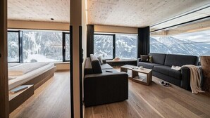 Un salon moderne avec une grande fenêtre, un canapé, une table basse et un plancher en bois.