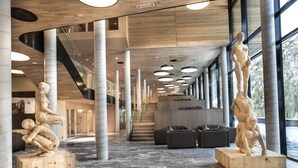 Un hall d’entrée spacieux, doté d’un sol en marbre, de grandes colonnes en bois et d’un éclairage moderne.