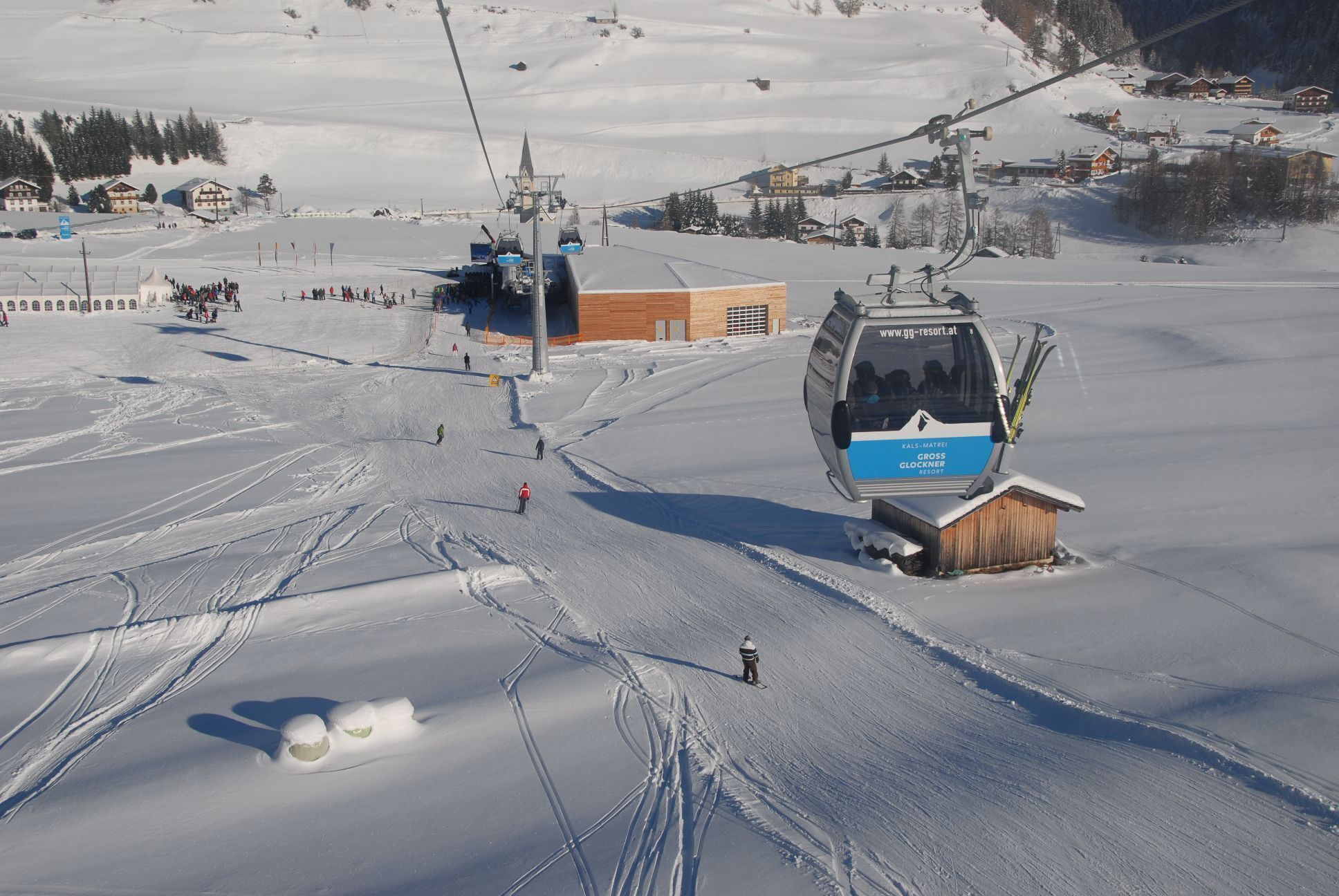 Eine Sesselbahn in einem Skiort, mit einem Holzbäude und einer Gondel.