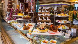 A buffet with various food items and desserts displayed on glass tables. - Harbourview Hotel Macau (Macau)