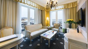 A hotel room with a sofa, armchairs, a coffee table, a TV, and a balcony with a view. - Harbourview Hotel Macau (Macau)