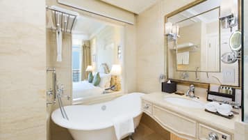 A bathroom with a freestanding bathtub, a large mirror, and a vanity with a sink and towel rack.