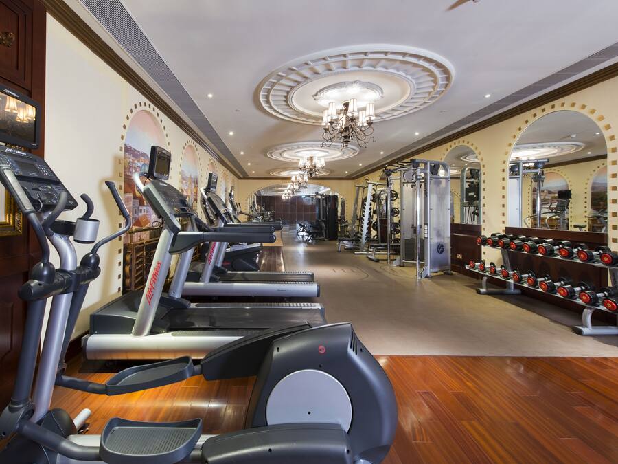 Une salle de sport équipée de tapis de course, de vélos elliptiques et d’un banc de musculation.