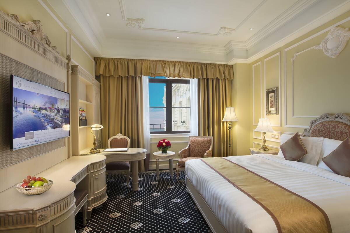 Ein Hotelzimmer mit Bett, Schreibtisch mit Stuhl, Fernseher und einem Fenster mit Vorhängen.