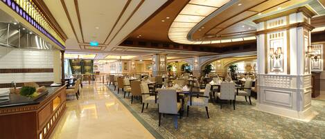 A spacious, elegantly decorated hotel lobby with a central island, multiple seating areas, and a grand chandelier.