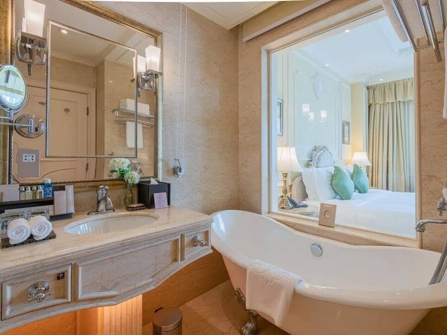 Un baño de hotel con un espejo grande, una bañera, un lavabo y un tocador.