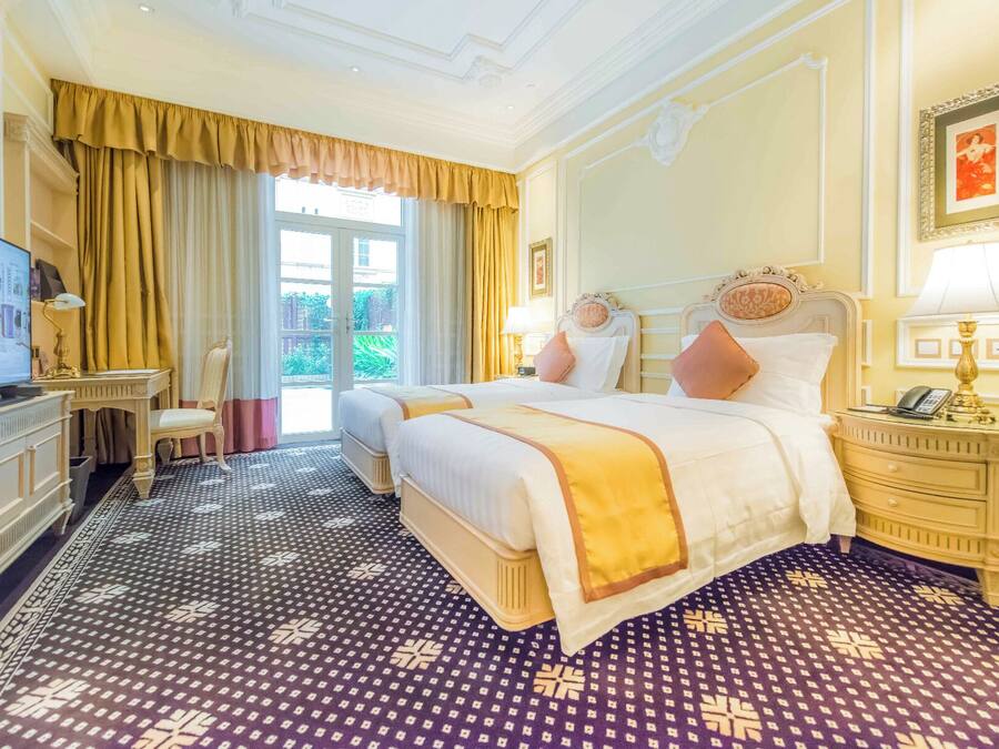 A hotel room with a large bed, a desk, a chair, a television, and a view of the outdoors.