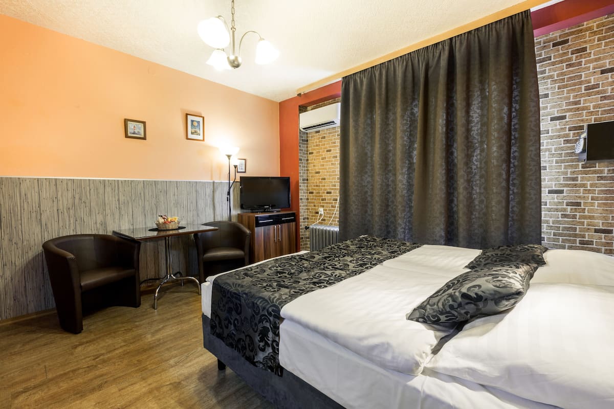Une chambre d’hôtel avec un lit, un bureau, une chaise, une télévision et un mur en briques.