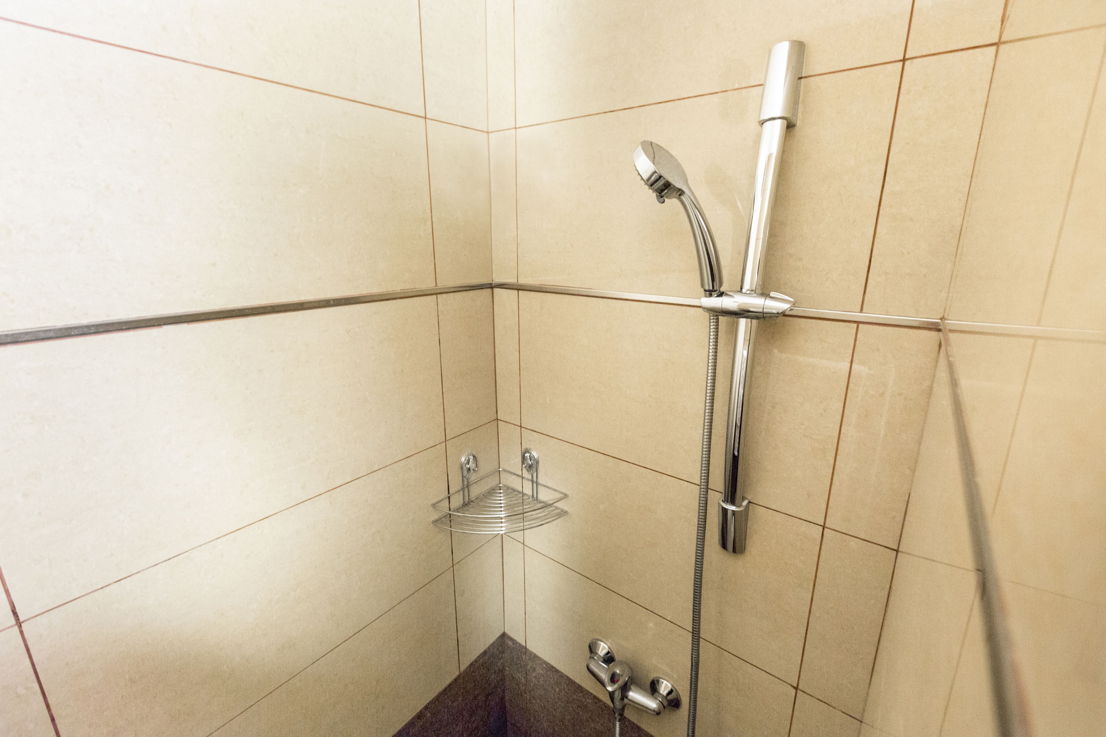 A small, tiled bathroom with a shower, a towel rack, and a soap dish.