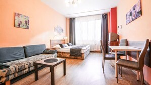 A modern living room with a sofa, a dining table, and a bed. - Rezidence Davids (Prague)