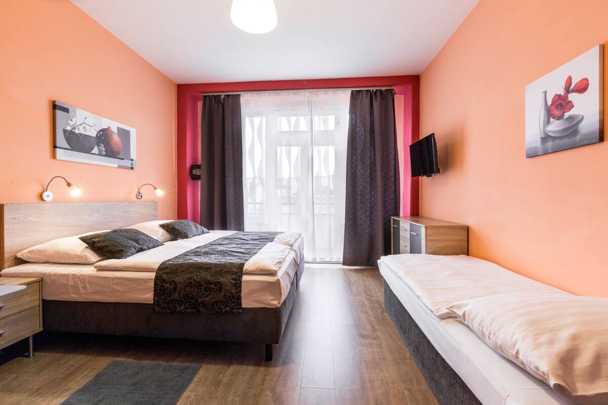 Une chambre à coucher avec un lit, des tables de chevet, une télévision et des œuvres d’art accrochées aux murs.