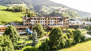 Um hotel com vários andares, piscina e paisagem montanhosa.