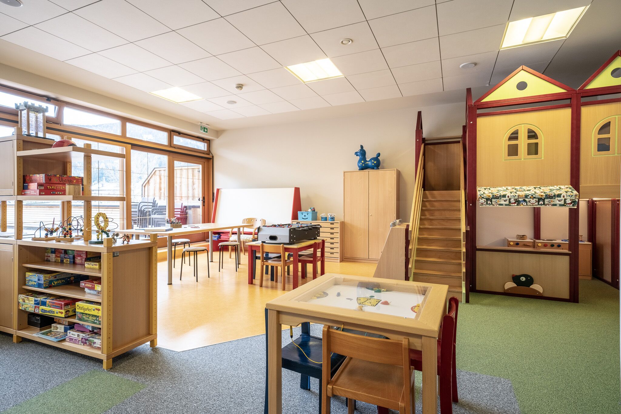 Ein Klassenzimmer mit Holzbeschlägen, einem Spielhäuschen und einer Treppe.