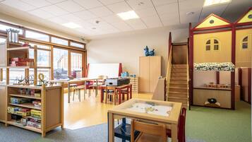 Ein Klassenzimmer mit Holzbeschlägen, einem Spielhäuschen und einer Treppe.