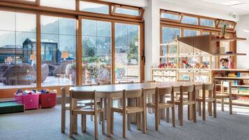 Learn and play in this well-equipped classroom with a long table, bookshelf, and play area.